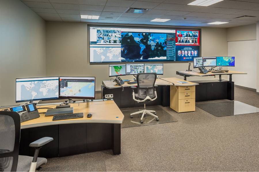 view of GSOC with three consoles and a video wall, featuring sit stand desk